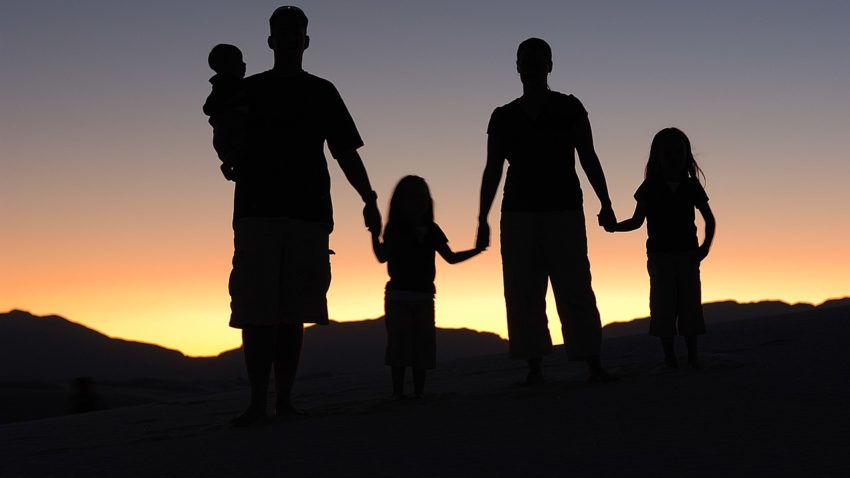 family silhouette standing in sunset